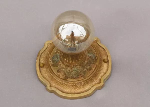 A gold plate with a glass globe on top of it.
