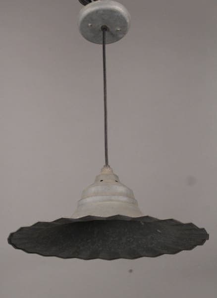 A vintage 10428. Industrial Pendant with Unusual Ruffled Edge with a wide, textured shade, suspended from a ceiling by a wire.