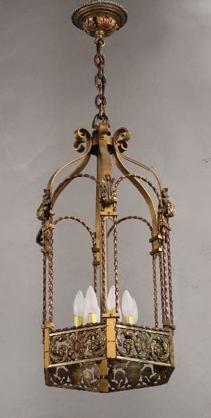 A Large Scale 1920's Spanish Revival Pendant with ornate gold detailing and four candle-like bulbs suspended from a chain.