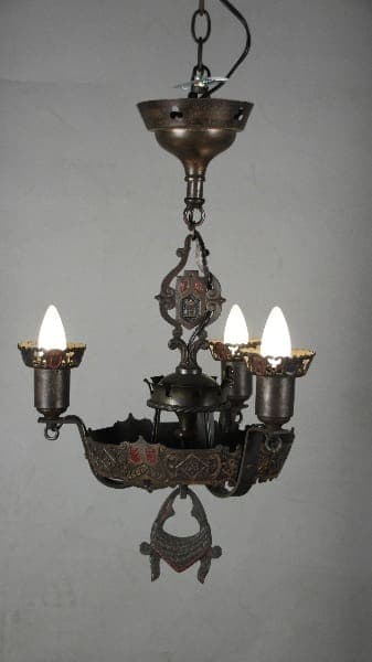 12047. 1920's Spanish Revival Polychrome Chandelier with ornate metalwork and three electric candles, hanging against a plain wall.