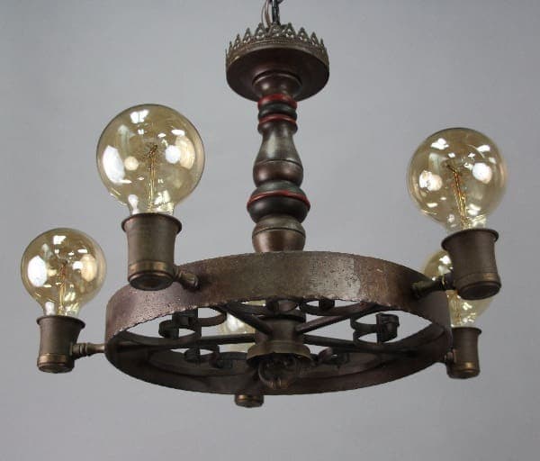 1920's Spanish Revival Monterey Style Chandelier with four glowing bulbs, metal frame, and decorative elements, suspended from a ceiling.