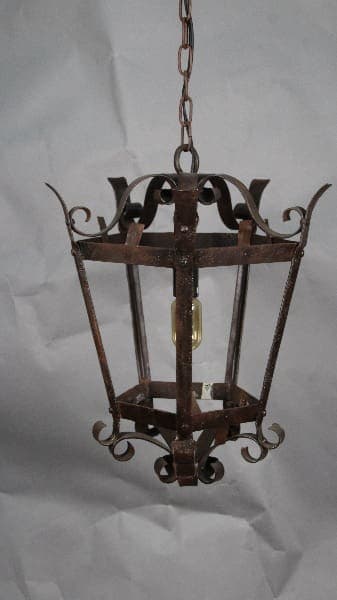 An old, rusty 13073. 1930 Simple Iron Pendant hanging from a chain against a crumpled white background.
