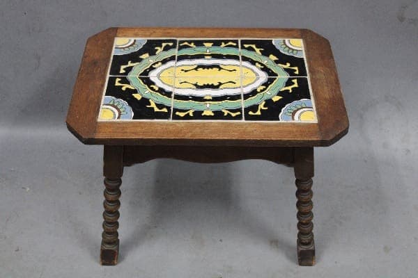 A 13981. 1920's Spanish Revival 6 Tile Table with a hexagonal top, intricately decorated with a black inlay featuring a yellow and white geometric design and central oval motif.