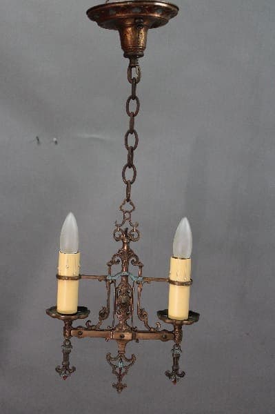 14526. 1920's Polychrome Pendant with two electric candles, intricate metalwork, and a chain hanging from a ceiling mount against a gray background.