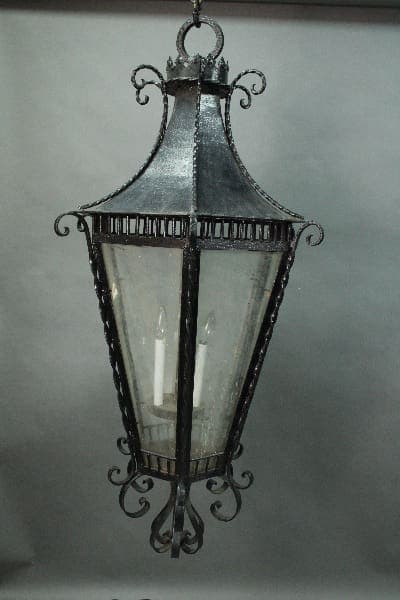 A vintage-style hanging lantern with metal frame and glass panels, featuring ornate details and containing two visible candle bulbs inside the 14599. Very Large 4 Ft High 1920's Original Iron Lantern.