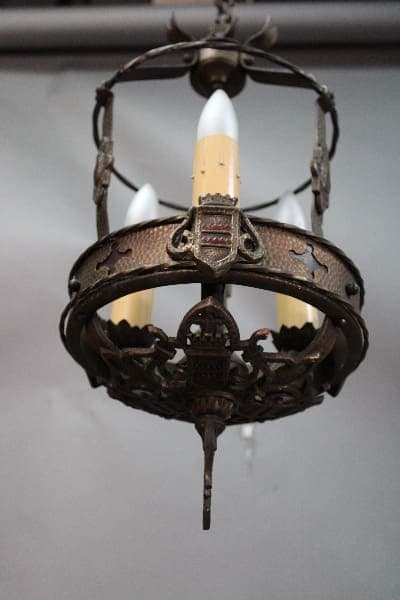 Antique chandelier with ornate metalwork and three candle-shaped bulbs hanging from a ceiling, such as the 14635. 1920's Three Light Pendant With Original Finish.