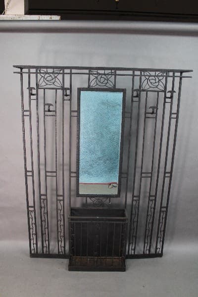 A decorative 14768. Rare 1920's Wrought Iron Coat Rack framing a vertical mirror with a textured blue surface, placed in front of a plain background.