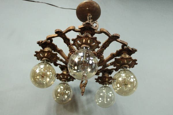 14832. Spanish Revival Four Light Chandelier with intricate designs, featuring five clear glass bulbs hanging from curved arms, set against a plain background.