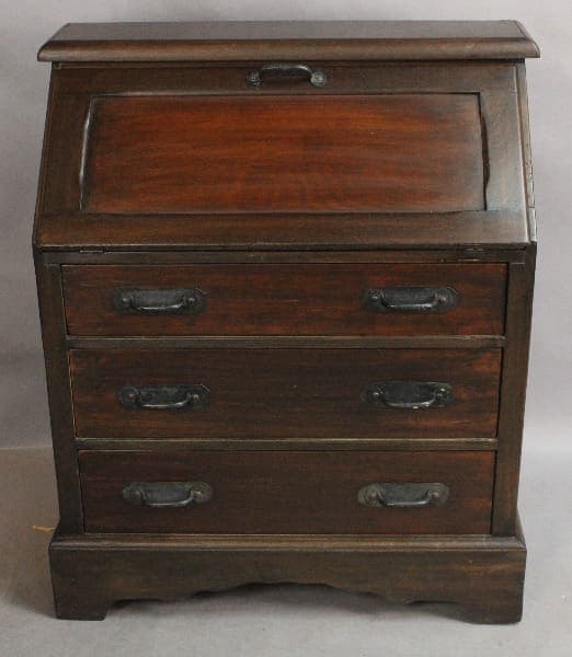 An antique 15096. 1920's Signed Monterey Desk with a slanted lift-top lid and three drawers with metal handles.