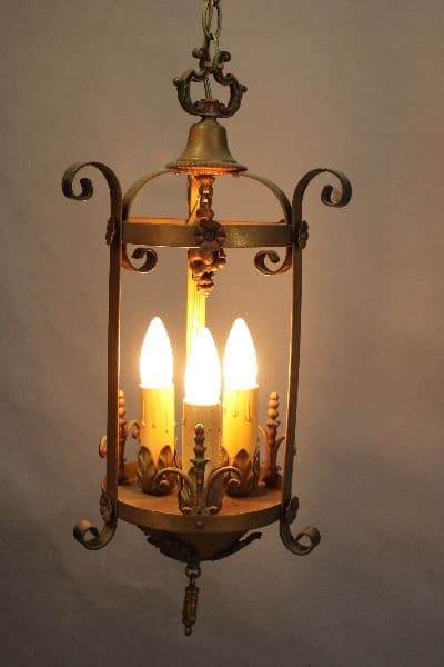 Vintage hanging lantern with 15389. 1920's Three Light Pendant With Original Polychrome Finish styled to look like candles, set against a plain background.