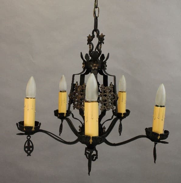 15448. Spanish Revival Five Light Chandelier With Crest Motif with five candle-shaped bulbs and ornate metal detailing, hanging against a gray background.