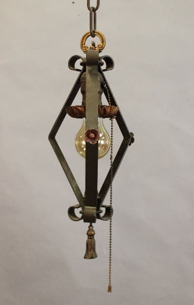 An ornate hanging light fixture with a 15486. Spanish Revival 1920's Pendant With Original Polychrome Finish, a central glass globe, and decorative elements including beads and tassels.