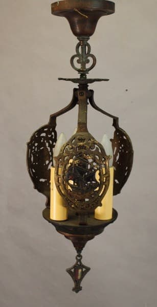 Antique hanging lamp with an ornate metal frame, featuring intricate cut-out patterns and a central yellow glass shade. Product Name: 15489. Polychrome Pendant With Galleon Motif