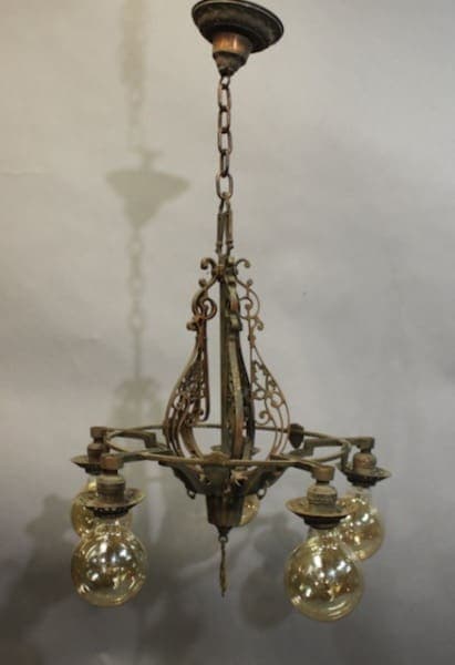 15958. Spanish Revival 1920's Chandelier With Five Lights with ornate metalwork and four glass globes hanging from a chain, against a blurred background.