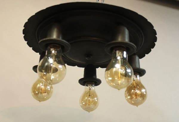 A black 15970. Circa 1920's Iron Ceiling Mount with five glowing, teardrop-shaped bulbs suspended underneath.