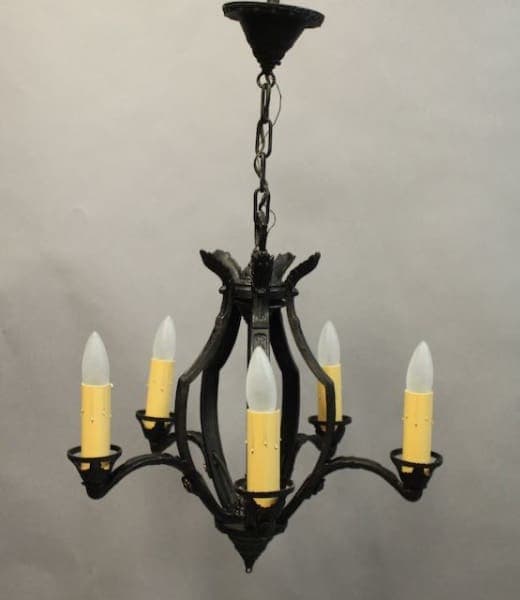 A black 16186. Circa 1920's Five Light Chandelier with five arms, each holding a white, candle-shaped light bulb, hangs from a chain against a gray background.