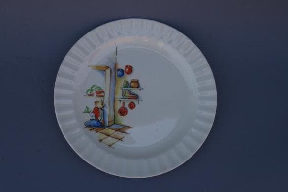 Decorative plate with a painted illustration of a food market scene, including fruits and a merchant, set against a plain blue background from the 3221. Set Of 12 Spanish Revival Plates.