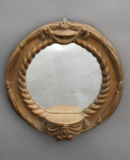 341. Small Round Mirror with an ornate wooden frame, featuring carved ribbons and floral motifs, hung on a gray wall.