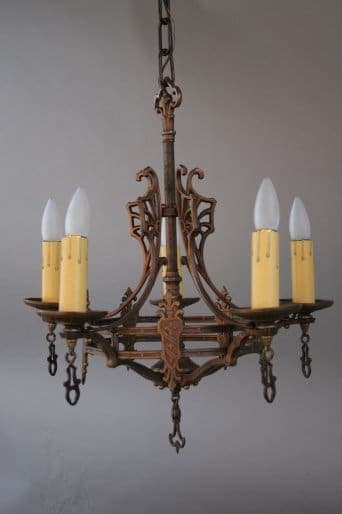 7256. Spanish Revival Chandelier With Crest Motif with ornate details, featuring five candle-shaped light bulbs against a gray background.