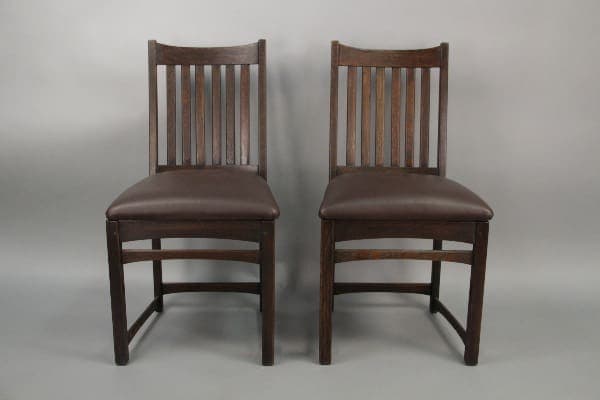 Two 10212. pairs of Arts & Crafts Oak Chairs with Soft, Curved Lines with brown upholstered seats and vertical slat backs, placed against a neutral gray background.
