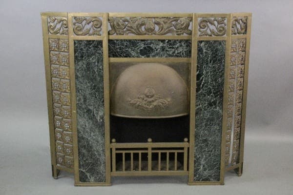 Antique 10317. Early 1900's Fireplace Surround with ornate gold detailing and a central panel featuring an embossed classical design on a metal medallion, flanked by green marble-like sections.