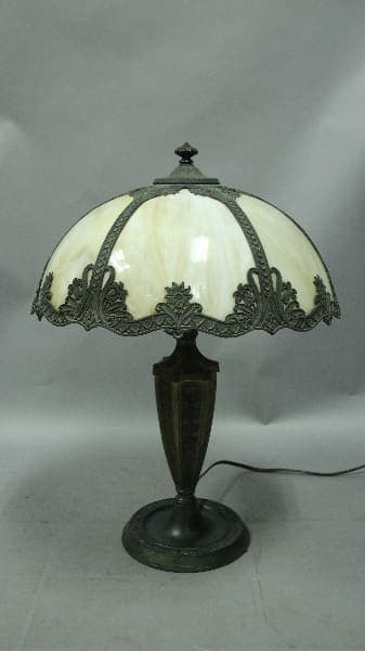 Vintage 12601. 1920's Table Lamp With Bell Shaped Slag Glass Shade with a curved white glass shade and ornate metal base on a gray background.