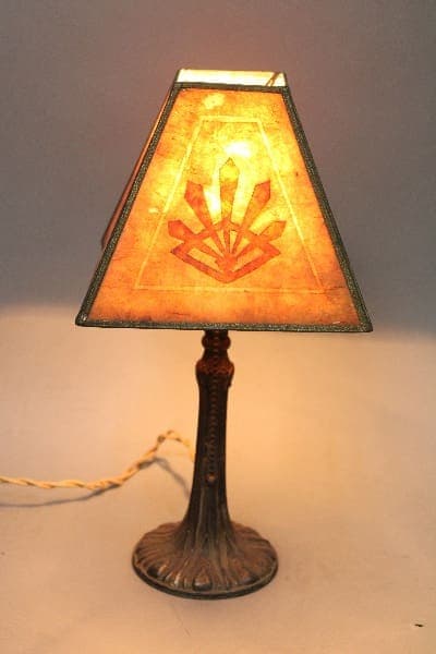 14873. Small Turn Of The Century Bronze Lamp With Mica Shade with an antique design, featuring a stained glass shade with a lotus-like motif on a decorative bronze base.
