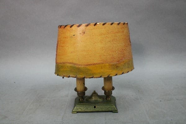 15027. 1920's Table Lamp With Green Base and Original Paper Shade with dual wooden posts, on a decorative brass base, displayed against a grey backdrop.