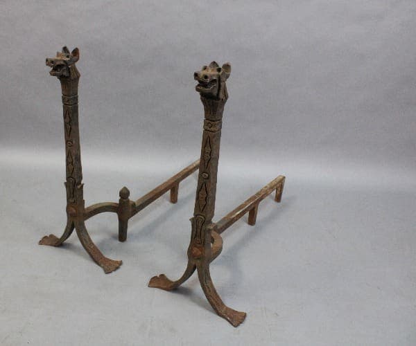 Two carved wooden 15335. Wrought Iron Pair Of Dragon Andirons with giraffe heads at the top, positioned on a light gray background.