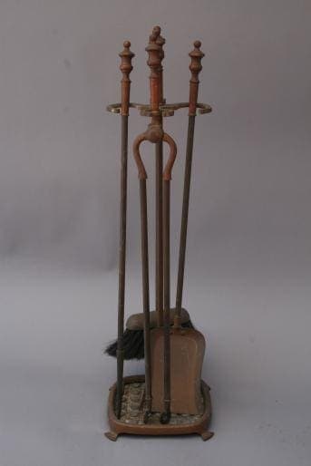 A set of 2415. Brass Fire Tool Set, including a broom, poker, and shovel, standing upright in a stand against a plain background.