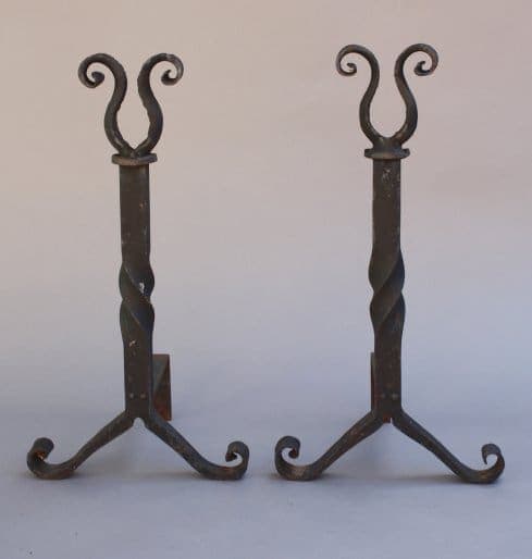 Sentence with product name: Two 7209. Pair Of Wrought Iron Andirons with spiral stems and curled top designs, standing on a plain background.