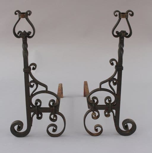 Two ornate Pair Of Wrought Iron Andirons with scroll designs on a light background.
