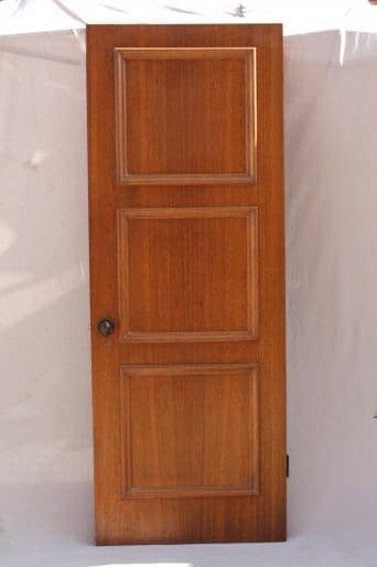 8290. 1920's Walnut Paneled Door with four panels and a round knob, standing isolated against a light fabric background.