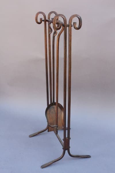 9550. Unique Copper Toned Fire Tool Set, consisting of a poker, shovel, broom, and stand, with decorative scrollwork, isolated on a light background.