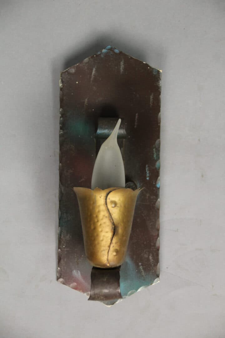 Wall-mounted candle holder with decorative design.