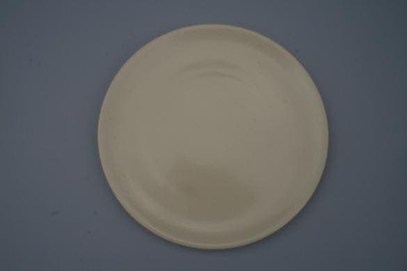 Plain round cream-colored plate on grey background.