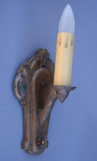 Bronze wall sconce with tapered light bulb.