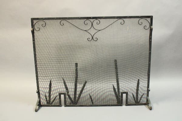 Decorative metal fireplace screen with mesh design.