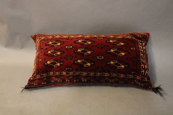Red patterned decorative pillow on gray background.