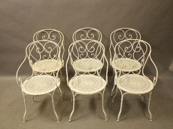 Six ornate white wrought iron chairs.