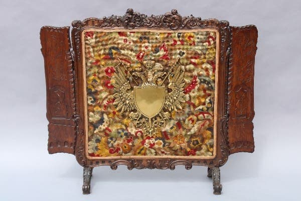 Ornate wooden screen with colorful embroidered panel.