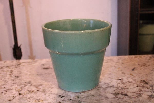 Green ceramic pot on marble surface.