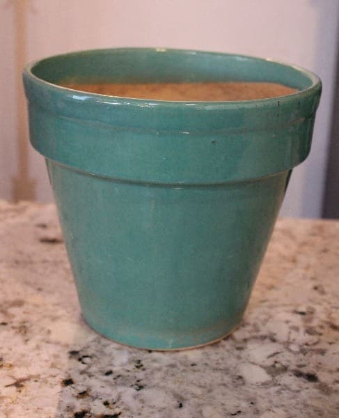 Green ceramic pot on a marble surface.
