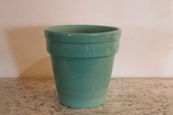 Green ceramic pot on a marble surface.