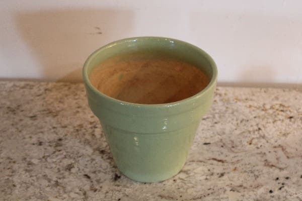 Green ceramic pot on a granite surface.