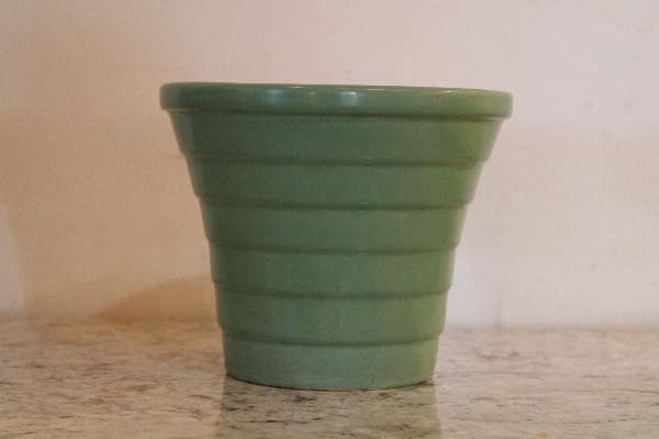 Green ceramic planter on marble surface.
