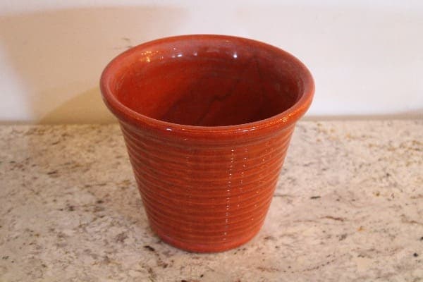 Red ceramic pot on a speckled surface.