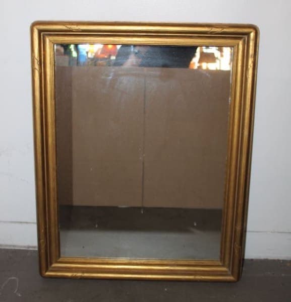 Gold-framed mirror against plain background.