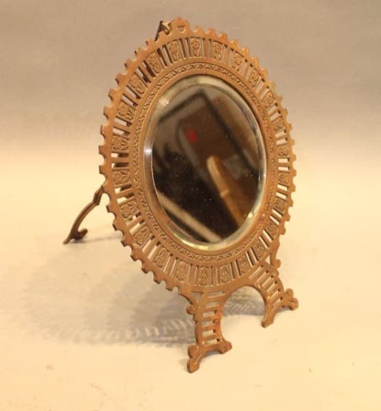 Antique oval mirror with ornate metal frame.