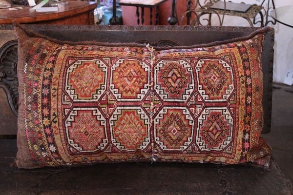 Ornate patterned pillow on wooden bench.